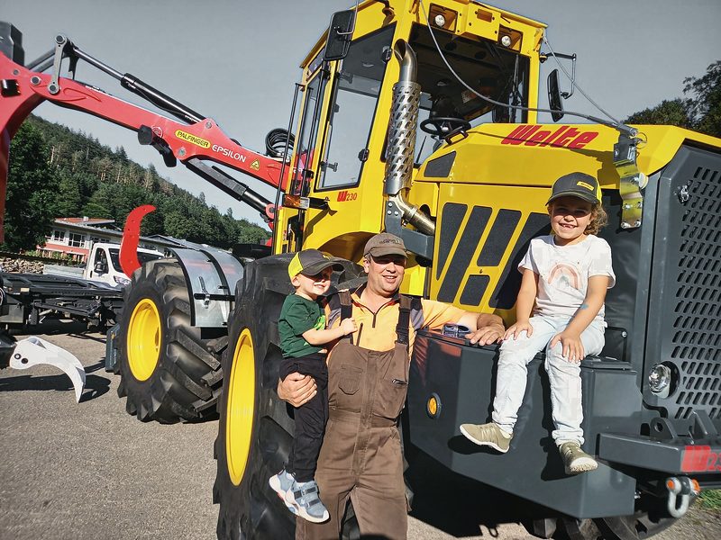 Inhaber mit zwei Kindern vor dem neuen Rückeschlepper