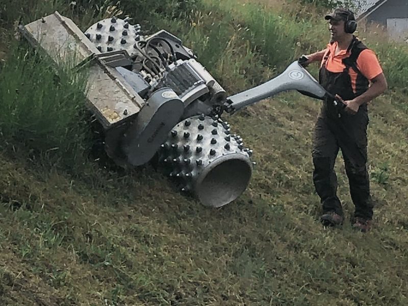 Mäharbeiten mit einem Hangmulcher an einer steilen Böschung