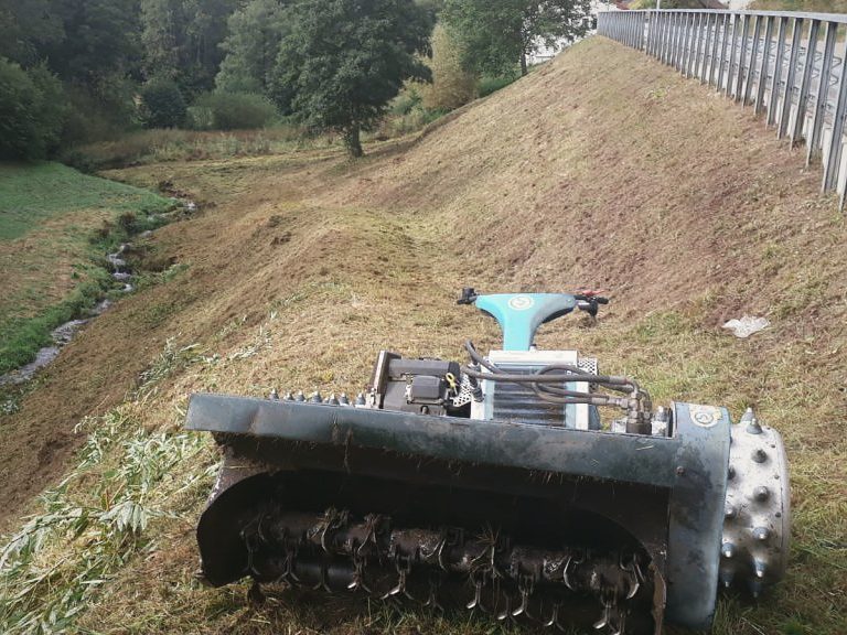 Hangmulcher an einer Bachböschung